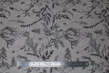Flat swatch taupe stags fabric (pale beige taupe fabric with tossed dark grey drawing style deer and forest emblems: feathers, leaves/greenery, trees, etc.)