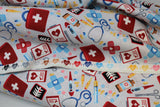 Raw hem swatch docs gadgets fabric (off white fabric with tossed full colour medical emblems: red first aid kits, black x-rays, white charts, coloured pills, blue stethoscopes, etc.)
