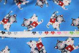 Raw hem swatch comfort kitties fabric (bright medium blue fabric with tossed cartoon grey and white snuggly kitties with red first aid kits)