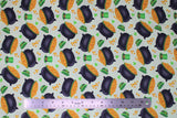 Flat swatch St. Patrick's Day themed fabric in pots of gold and green hats tossed on white