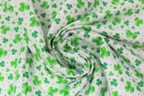 Swirled swatch St. Patrick's Day themed fabric in assorted green shamrocks on white