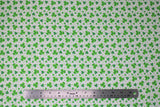 Flat swatch St. Patrick's Day themed fabric in assorted green shamrocks on white
