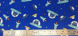 Flat swatch cartoon UFO and aliens printed fabric in blue (bright medium blue fabric with tossed blue cartoon aliens in small teal UFOs with tossed yellow and blue UFOs, teal rocketships, and tossed stars in various colours)