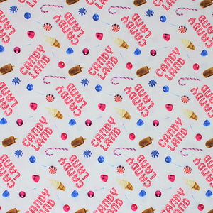Square swatch Candy Land fabric (white fabric with tossed "Candy Land" text in candy cane letters, tossed treats candy canes, fudgesicles, vanilla ice cream cones, candies in blue, pink, red)