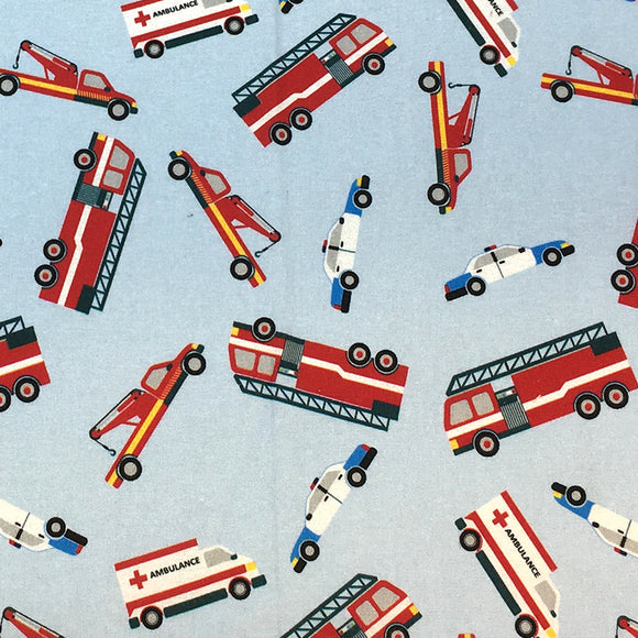 Swatch of cartoon emergency vehicle printed fabric in blue (pale light blue fabric with tossed cartoon police cars, firetrucks and ambulances)