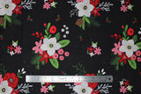 Flat swatch Floral fabric (black fabric with tossed large cartoon style floral clusters with white, red, and pink floral heads and greenery, brown pinecones and tossed holly, scattered tiny white snow dots)