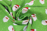Swirled swatch Santa Toss fabric (green fabric with white snow dots scattered and tossed smiling santa heads in an assortment of skin tones with red hats on)