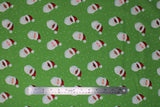 Flat swatch Santa Toss fabric (green fabric with white snow dots scattered and tossed smiling santa heads in an assortment of skin tones with red hats on)