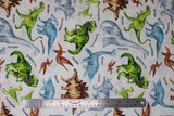Flat swatch Dino World White fabric (white fabric with illustrative look dinosaurs in full colour: green, brown, and blue varying types with black text labels)