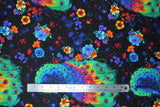 Flat swatch peacock and flowers fabric (black fabric with tossed blue-bodied rainbow-feathered peacocks, tossed wispy floral lines in blue, orange, red, pink, purple, yellow)