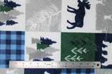 Flat swatch cabin quilt navy fabric (quilt squares look fabric with cabin themed squares, moose, pinecones, bears, trees etc. in white, grey, green and blue colourway)