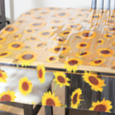 Square photo clear vinyl tablecloth draped over table (clear with sunflower heads print)