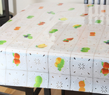 Square photo clear vinyl tablecloth draped over table (white quilt pattern with assorted fruits in every other square alternating)