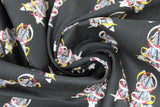 Swirled swatch feather themed print in feathers black (black solid fabric with repeated feather design two white/grey feathers crossing with white/red/yellow ribbons wrapping around)