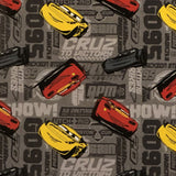 Square swatch Disney's Cars printed fabric (grey fabric with car related text in various greys assorted and drawn red, yellow, and black car characters)