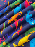 Swirled swatch knit material in colourful dino (yellow, green, blue, pink, orange cartoon dinosaurs on dark blue)