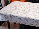 Purple Flower (delicate purple flowers with green stems and leaves scattered over a white background) opaque vinyl draped over a dining room table with matching chairs around it.