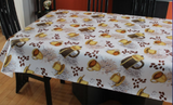 Coffee (scattered yellow mugs filled with brown liquid, yellow cup and saucer sets, black basket with yellow trim, and clusters of coffee beans on a white background) opaque vinyl draped over a dining room table with matching chairs around it.
