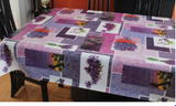 Lavender (lavender, indigo and mauve printed rectangles overlap each other along with white rectangles featuring pictures of lavender sprigs, baskets of lavender, or lavender fields) opaque vinyl draped over a dining room table with matching chairs around it.