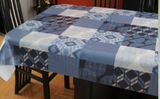 Blue decor (squares of blue geometric elements such as chevrons and overlapping circles in shades of navy, mid blue, pastel blue and white) opaque vinyl draped over a dining room table with matching chairs around it.