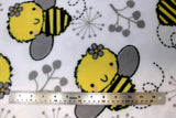 Flat swatch FLC fleece print in Izzy Bee (happy cartoon bumble bees and grey plant shapes on white)