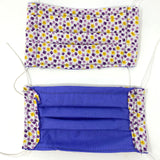 Front and back view of mask with white elastic ear loops (white mask with tiny purple and yellow floral heads allover and dark purple small squares)