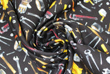 Swirled swatch Tossed Tools fabric (black fabric with tossed tools allover in drawn style, full colour: hammers, wrenches, nails, screws, tape measures, gloves, tape, etc.)