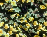 Swirled swatch Bloom Sateen Print fabric (black fabric with realistic look floral allover in white and yellow and pale purple on branches)
