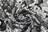 Swirled swatch Black Sugar Skulls fabric (black fabric with busy tossed white and grey decorative skulls with floral accents allover, sugar skull style)