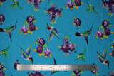Flat swatch hummingbirds fabric (bright medium blue fabric with tossed purple floral with yellow/green stems and assorted blue/green/purple/yellow hummingbirds)