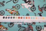Raw hem swatch cat themed fabric in bike race (light blue turquoise coloured fabric with assorted cartoon cats on regular and tandem bikes)
