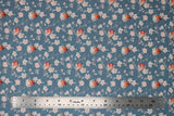 Flat swatch Linotte fabric (pale blue/grey fabric with grey branches and white/pink cherry blossom look flowers allover with little birds sitting on branches in white, grey with orange faces/bellies)