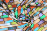 Swirled swatch Santorin fabric (barn board style fabric arrange in a brick like pattern in grey, brown, orange, purple, green, blue)