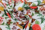 Swirled swatch white floral fabric (white fabric with repeated floral and butterfly pattern, medium sized pink, yellow and purple flowers with large green stems and orange, yellow butterflies)