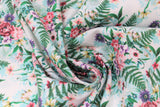 Swirled swatch large floral fabric (white fabric with large light blue floral silhouettes allover and repeated floral bouquet style graphics in pink and purple floral with greenery)