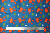 Flat swatch (side 2) Poulpy fabric (blue fabric with tossed smiling orange cartoon style crabs with arms up, loosely scattered white dots and green dot clusters)