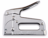 A silver staple gun, trigger arching up and to the right above the rounded grip. Some faint, illegible text is etched into the bottom edge of the handle.