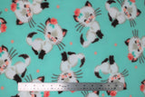 Flat swatch happy kittens fabric (light blue/green fabric with tossed white and black Siamese look smiling kittens eyes closed with pink rose on one side of ear and tossed pink polka dots)