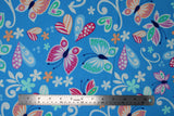 Flat swatch butterflies fabric (blue fabric with large tossed applique style butterflies, hearts, flower heads, and swirls in white, blue, pink, orange, green, teal, purple)