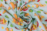 Swirled swatch taco chihuahua fabric (teal fabric with tossed cartoon yellow and orange tortilla chips, green and red peppers/chilis, green lime wedges and green avocado halves with repeated pattern of tan chihuahua dogs with a hard shell taco for a body, wearing a sombrero)