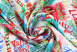 Swirled swatch Mistle-Toad fabric (white and rainbow splotched fabric with multi directional and multicoloured text allover related to christmas and frogs "Mistle Toad" "Neck the Halls")