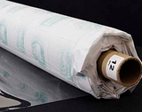 A partly unfurled roll of clear soft vinyl with white backing paper covered in green motifs. The end of the roll has a label with a 12 on it.
