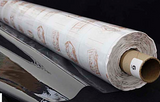 A partly unfurled roll of clear soft vinyl with white backing paper covered in brown motifs. The end of the roll has a label with a 6 on it.