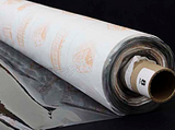 A partly unfurled roll of clear soft vinyl with white backing paper covered in orange motifs. The end of the roll has a label with a 8 on it.