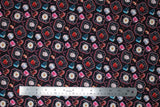 Flat swatch hot cocoa fabric (black fabric with tossed mugs of hot cocoa in many different styles: with and without saucers, whipped cream, white mugs, pink mugs, blue mugs, red mugs, clear mugs, some in small black badges with red outlines and tossed candy canes)