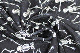 Swirled swatch Dancing Skeleton fabric (black subtle distressed look fabric with tossed white smiling skeletons allover in various dance poses)