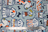 Flat swatch polka dot dogs fabric (light grey fabric with assorted size and breed cartoon dog outlines in blue, filled in white with polka dot and stripe details, tossed navy dog bones, all in an orange, navy, yellow colourway)