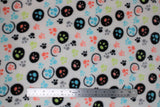 Flat swatch colourful paws white fabric (white fabric with small tossed paw prints in lime green, pale coral, blue, grey, black some plain, some with black circle outlines and some with solid black polka dot backgrounds)