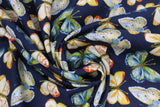 Swirled swatch fabric in butterflies (dark blue/black fabric with medium sized butterflies in diagonal rows in white, yellow, orange, blue, green colourway)