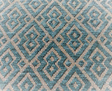 Turquoise-blue colourway of this jacquard geometric pattern with turquoise-blue in a velvety texture and cream for background. Pairs of joined diamonds resembling a mask are outlined by a second line of the same thickness